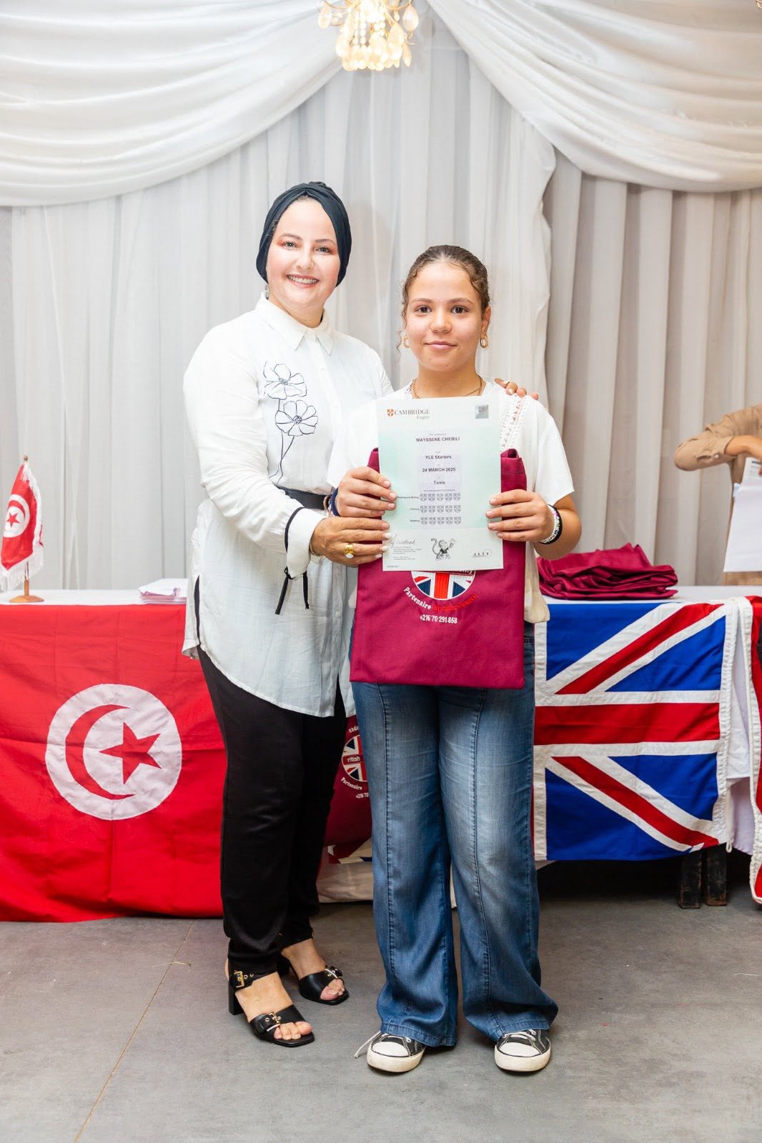 Student holding her Cambridge English YLE certificate with her teacher