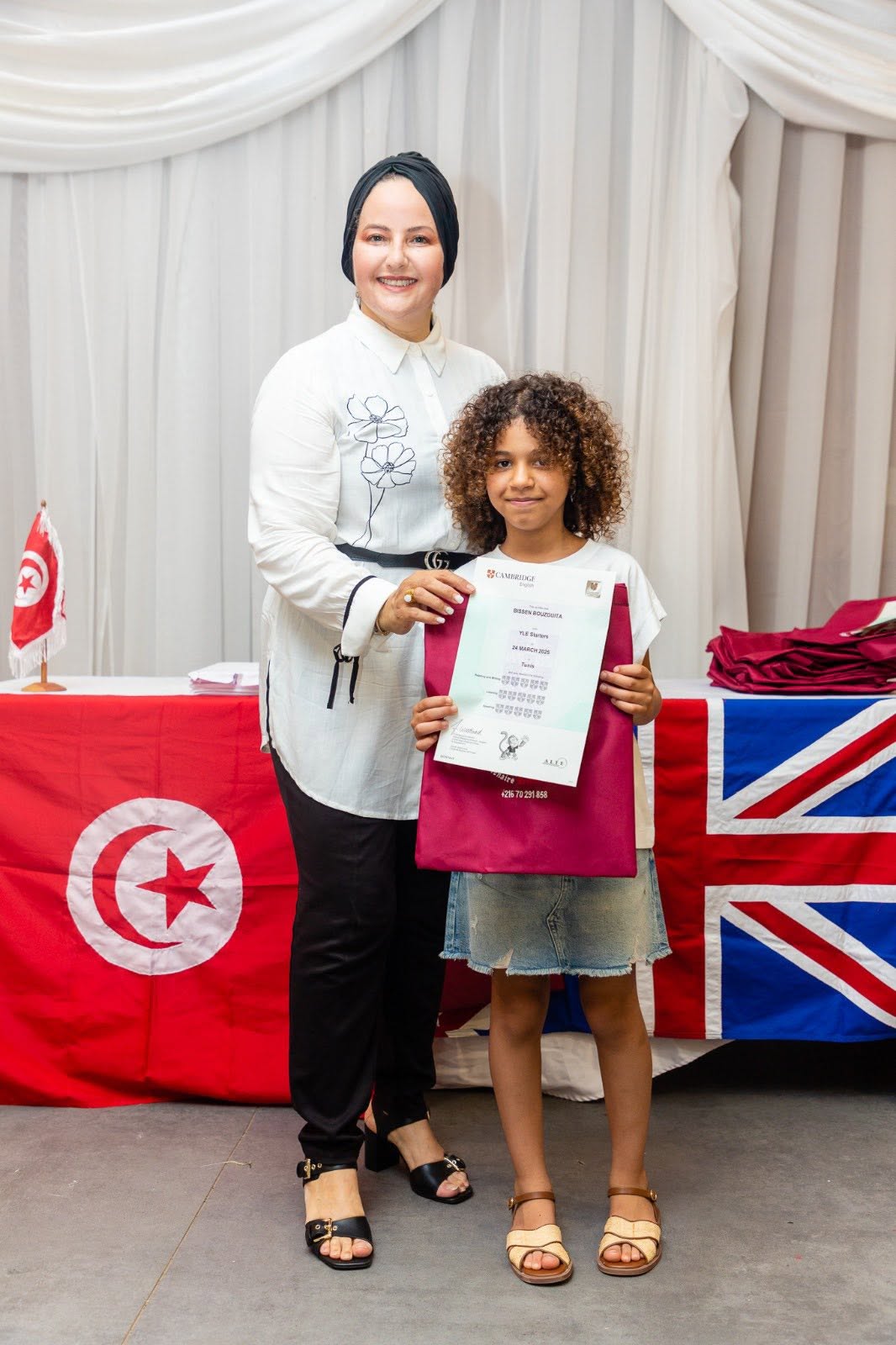 Student holding her Cambridge English YLE certificate with her teacher