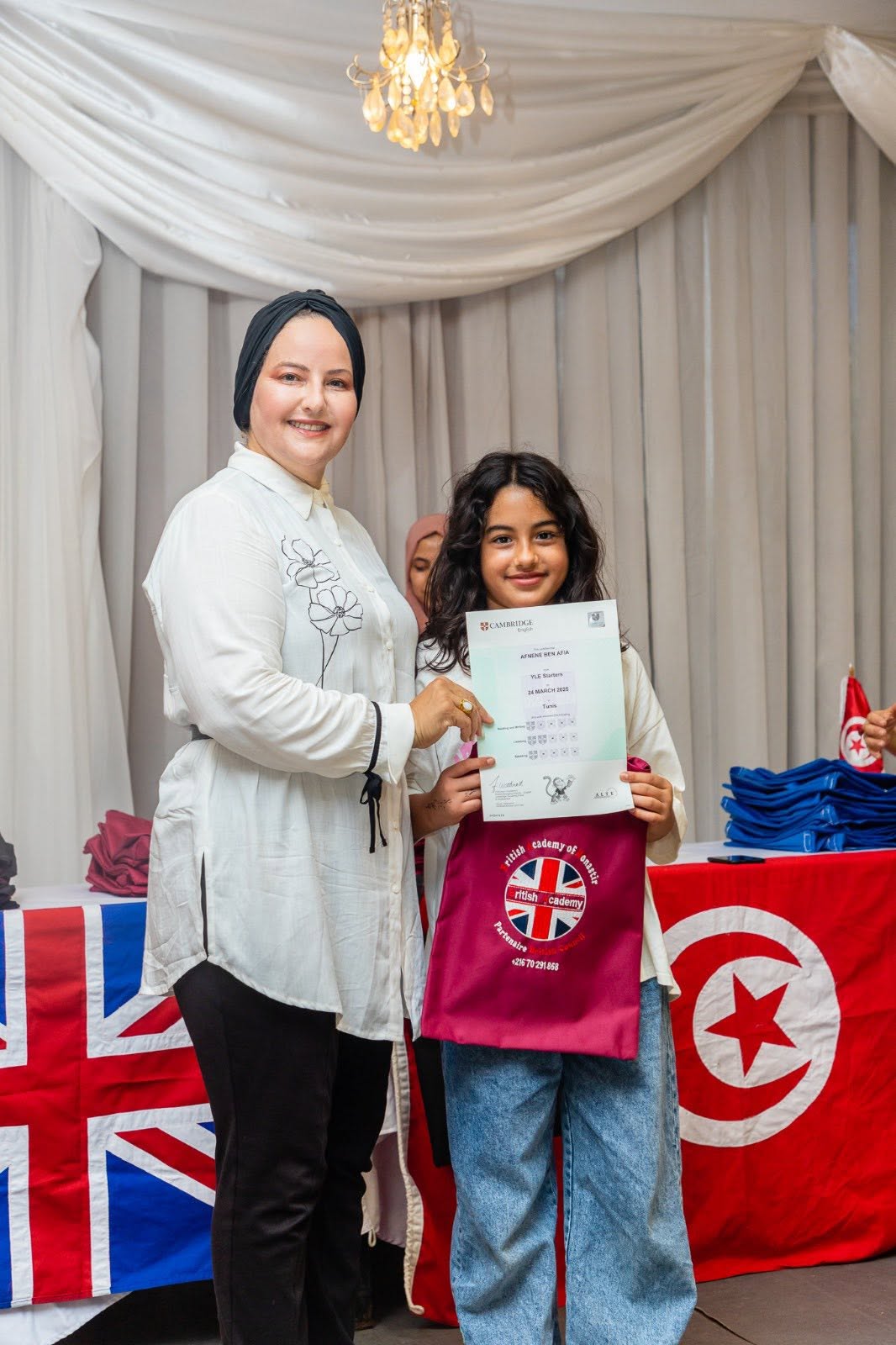 Student holding her Cambridge English YLE certificate with her teacher