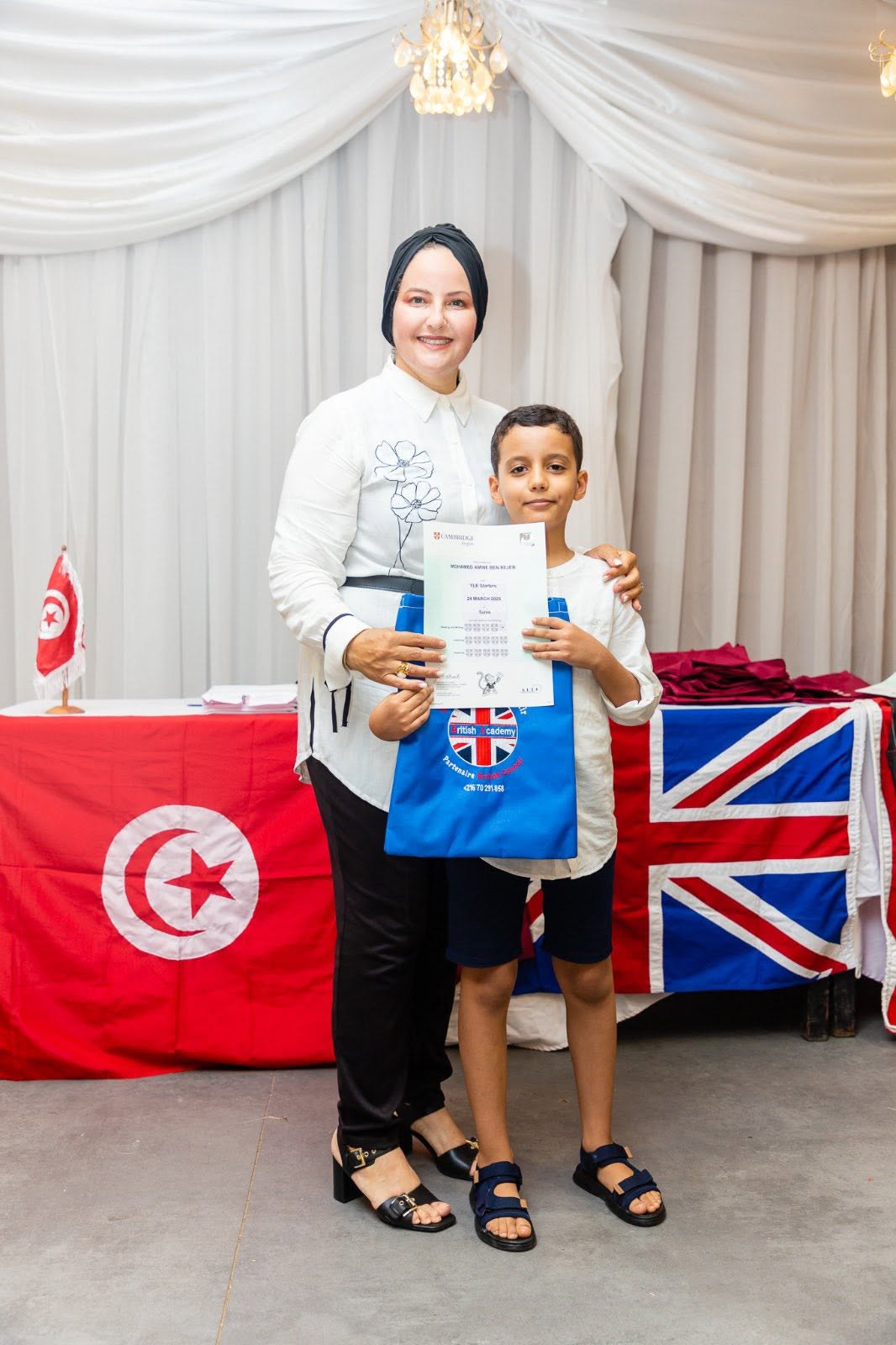 Student holding his Cambridge English YLE certificate with his teacher