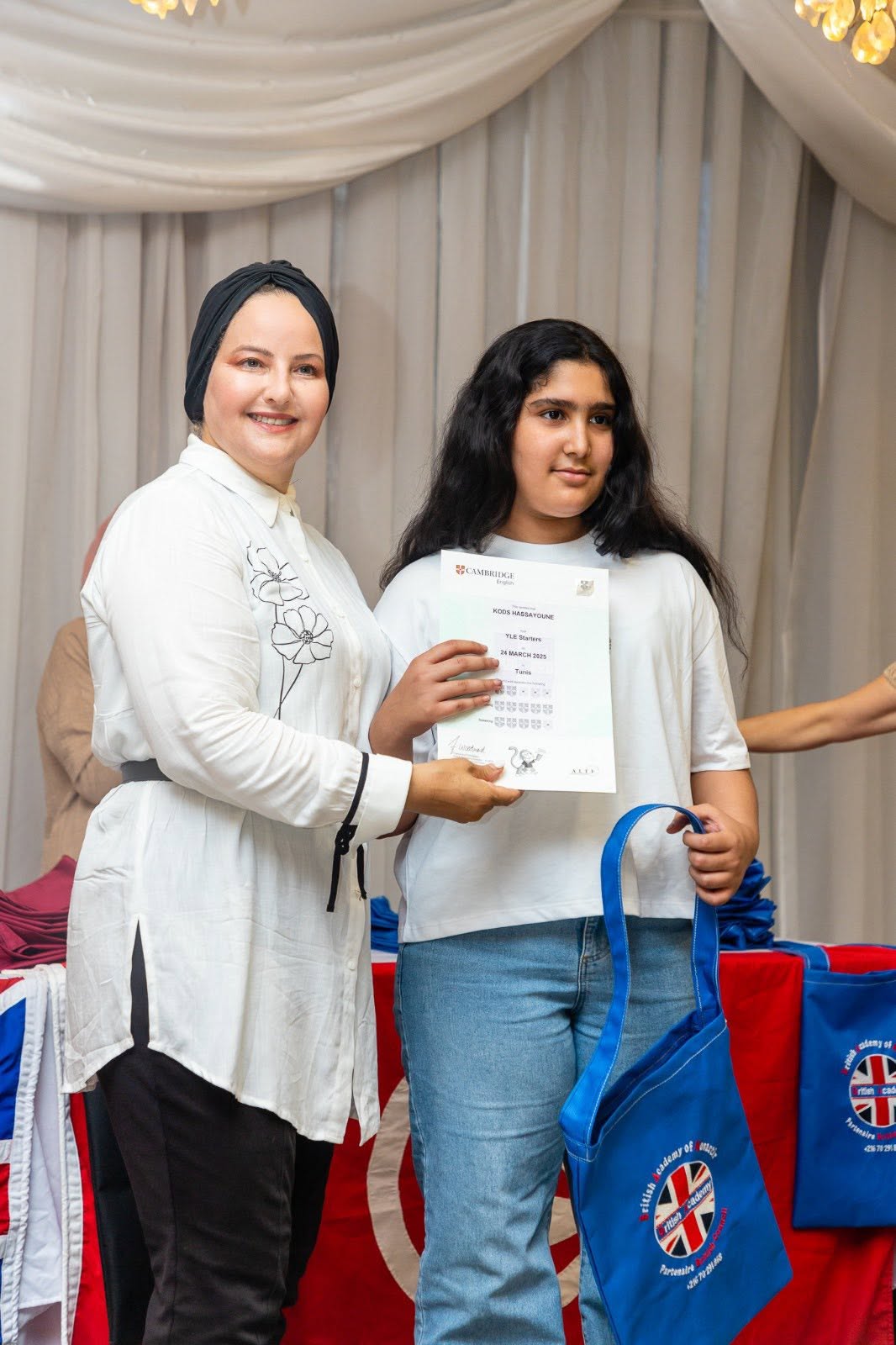 Teen student holding her Cambridge English YLE certificate with her teacher