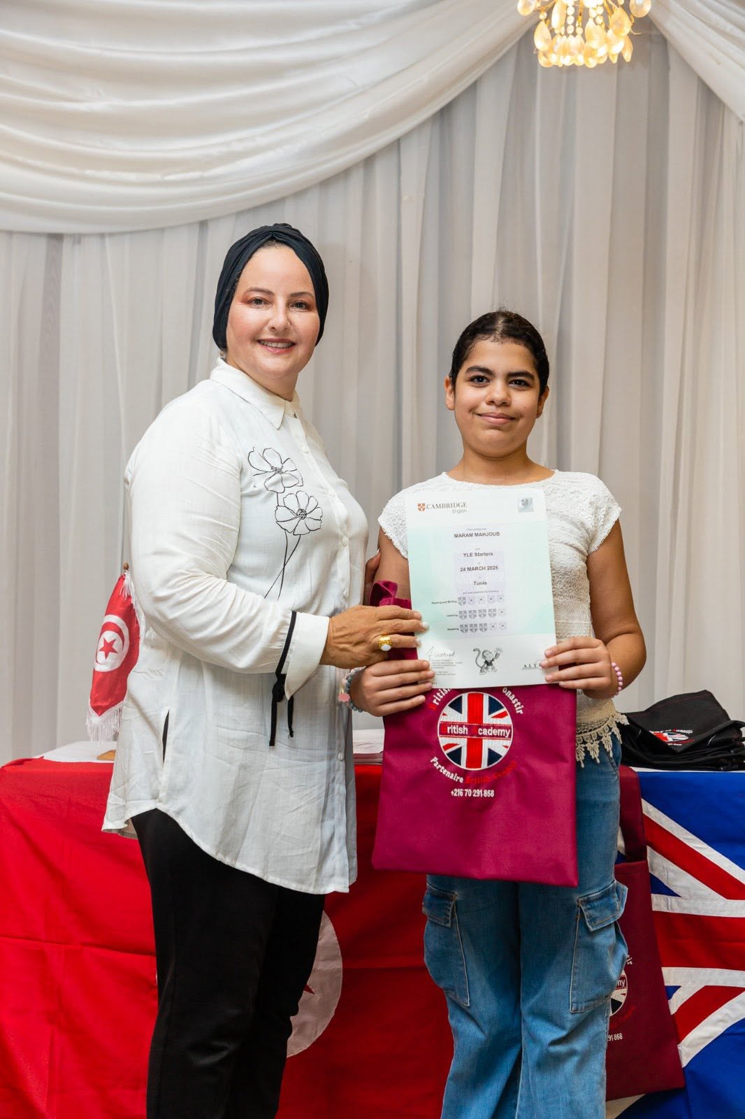 Teen student holding her Cambridge English YLE certificate with her teacher