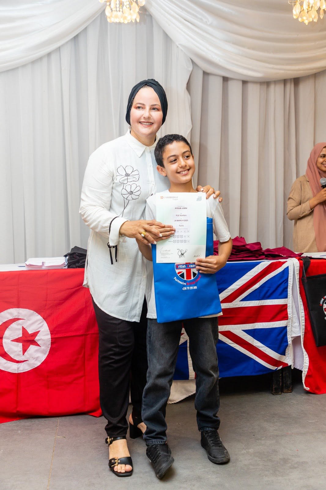 Student holding his Cambridge English YLE certificate, celebrated by his teacher