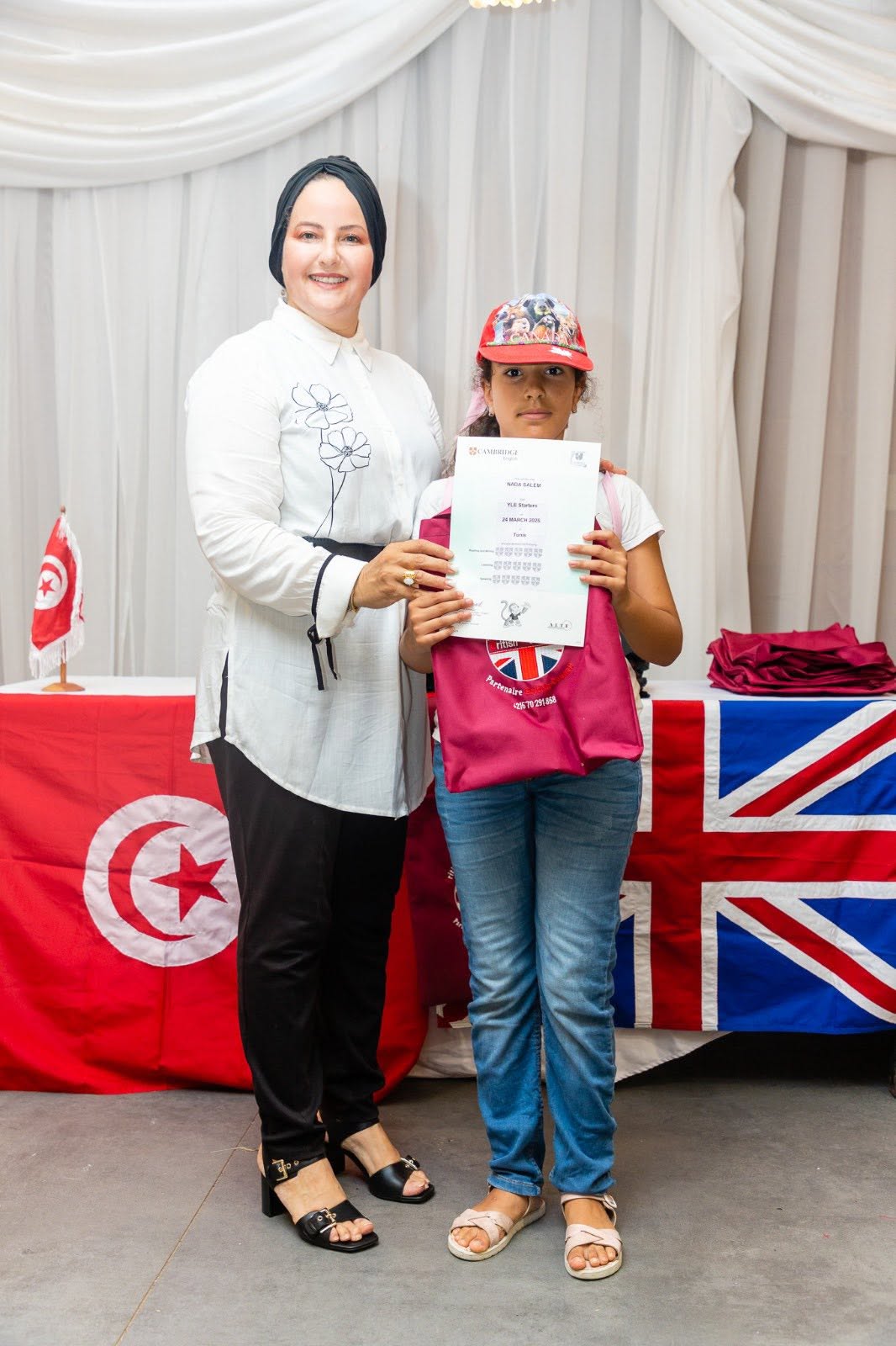 Student holding her Cambridge English YLE certificate with her teacher