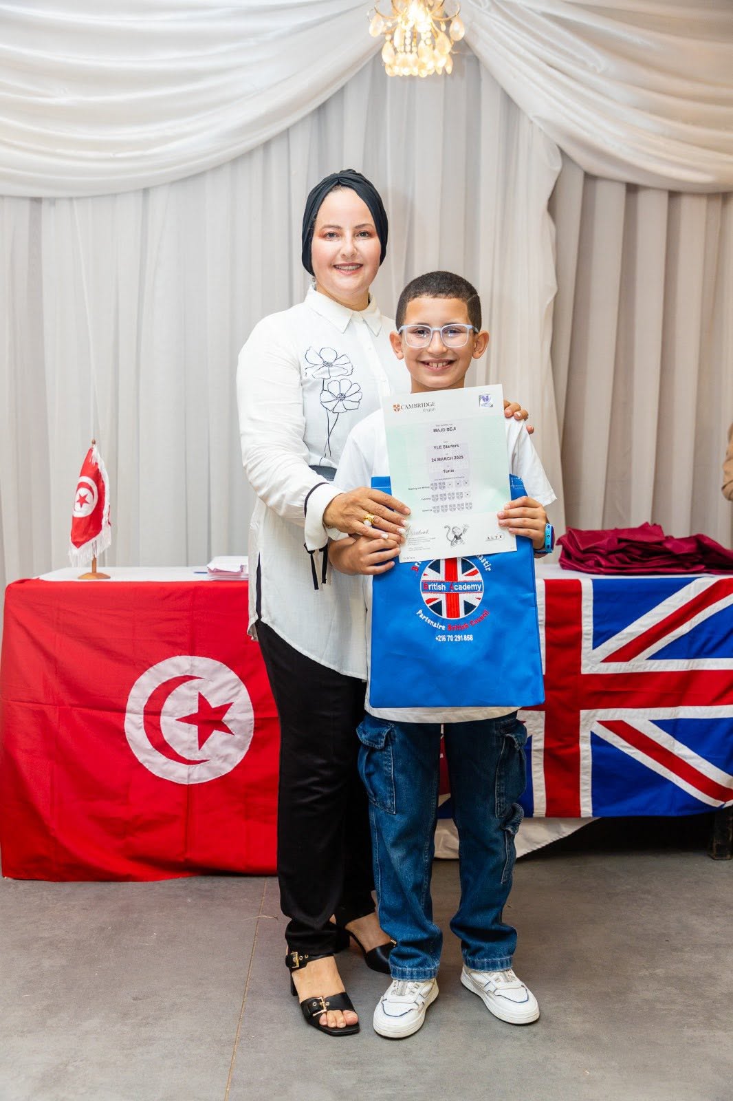 Student holding his Cambridge English YLE certificate with his teacher