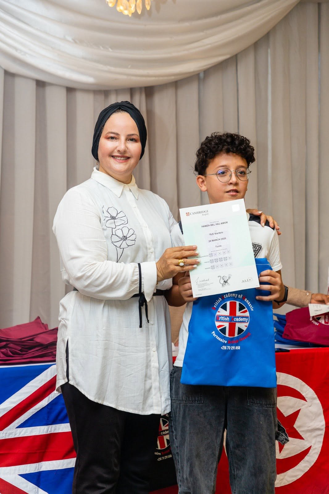 Student holding his Cambridge English YLE certificate with his teacher
