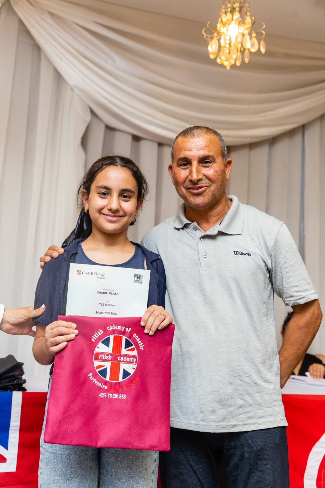Student and her father holding her Cambridge English YLE certificate